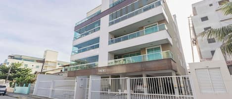 Un immeuble à plusieurs étages doté d’une entrée sécurisée par un portail, de balcons et d’une enseigne sur laquelle on peut lire « ARUBA ».