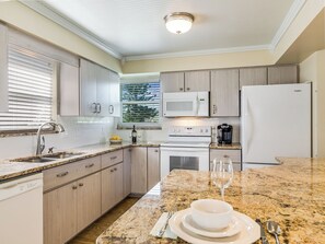 Enjoy cooking in this well-equipped kitchen with a large window offering a view of the outdoors.