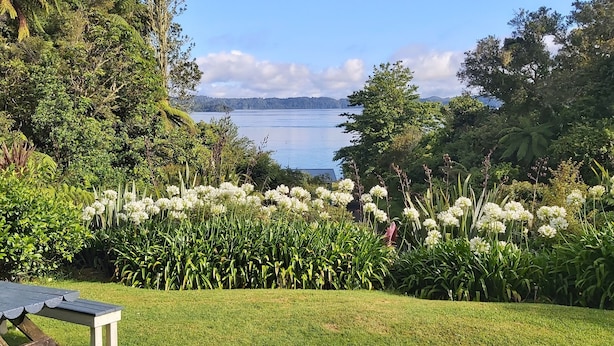 A garden with a table and umbrella, a lake view, and lush greenery.
