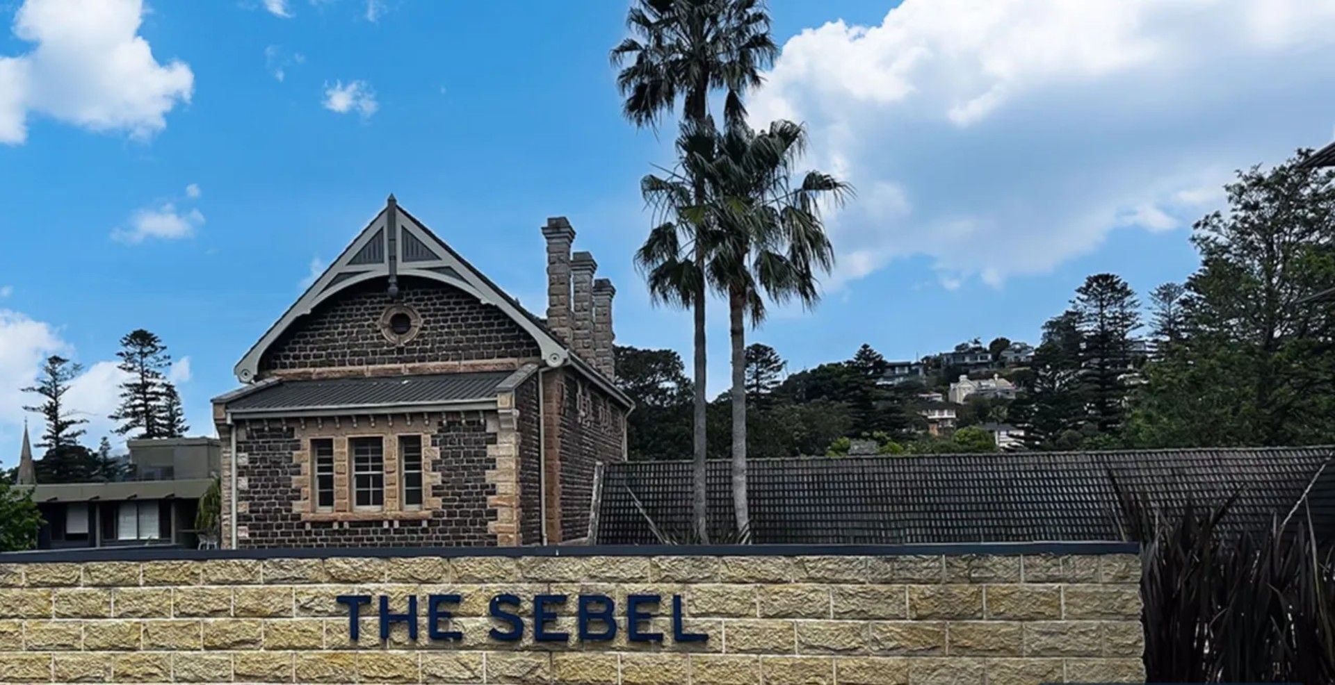 A stone building with a triangular roof and a sign that reads "THE SEBEL".
