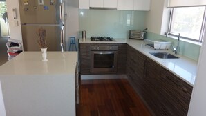 Een moderne keuken met een inbouwoven, gasfornuis, broodrooster en spoelbak.