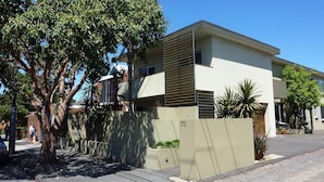 Een modern, twee verdiepingen hoog gebouw met een plat dak en een balkon op de bovenste verdieping.