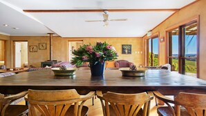 A spacious dining area with a large wooden table, several chairs, and a ceiling fan. - The Farmhouse — Relax in a rustic private sanctuary, pet and family friendly (Canyonleigh)