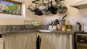 A kitchen with hanging pots, a sink, a stove, and various utensils. - The Farmhouse — Relax in a rustic private sanctuary, pet and family friendly (Canyonleigh)