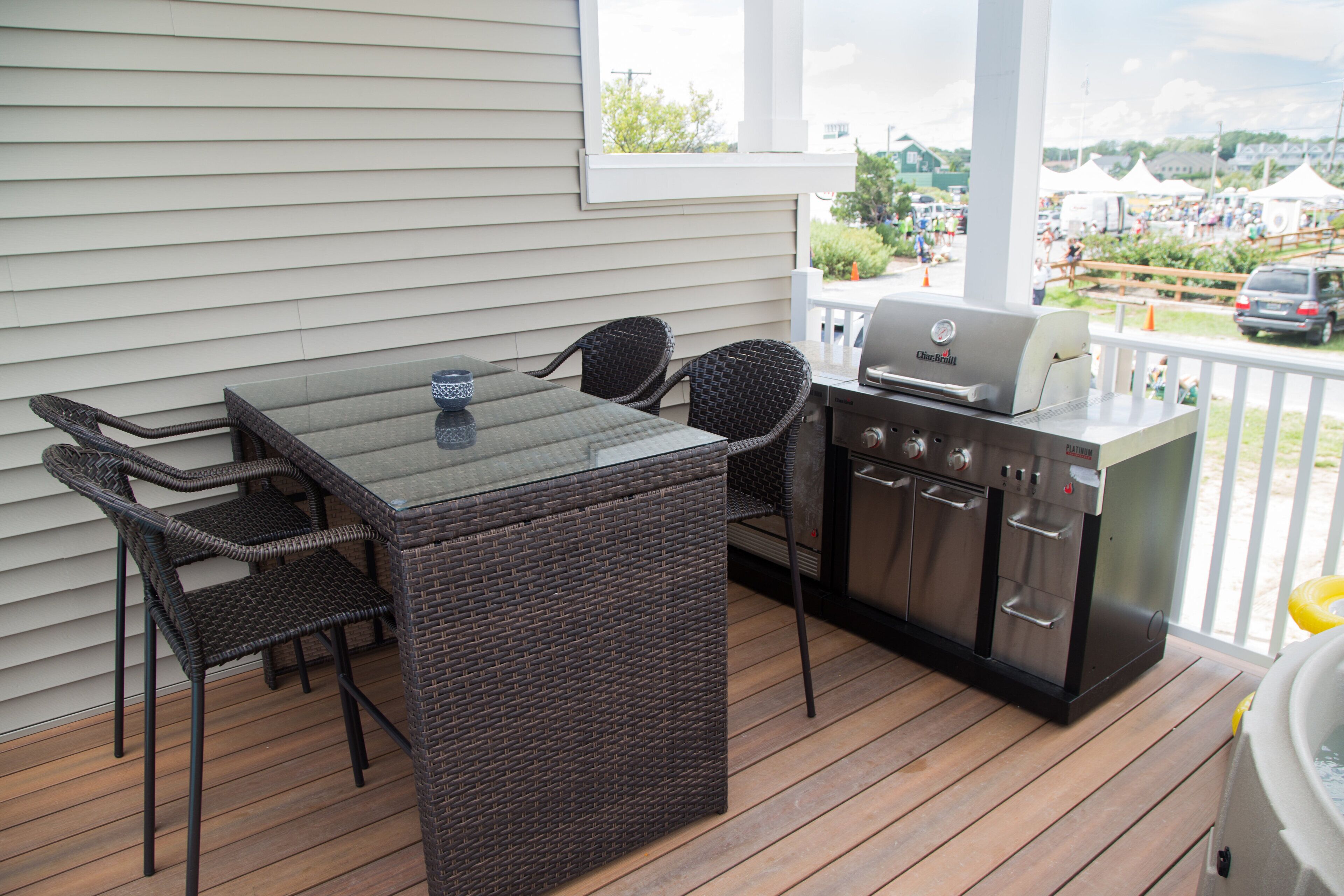 An outdoor patio with a glass-top table, wicker chairs, and a built-in grill.