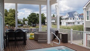 Une terrasse en bois avec une piscine, du mobilier d’extérieur et une rambarde blanche.