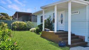 A two-story house with a front porch, a well-maintained lawn, and a small garden.