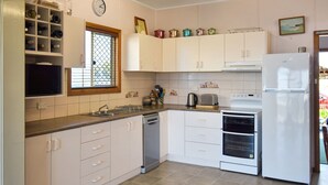 A kitchen with white cabinets, a sink, a dishwasher, a stove, and a refrigerator.