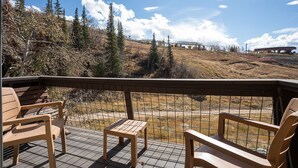 Une terrasse en bois avec des sièges extérieurs et une vue sur un paysage montagneux.