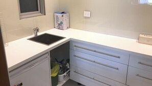 A modern kitchen with a black sink, white cabinets, and a window above the sink. - Balgowlah 2 Bedroom Flat 100 metres down steps to Jilling Cove (Balgowlah)