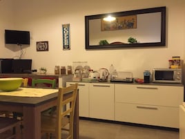 Una cucina compatta con tavolo e sedie, un forno a microonde, un bollitore e diversi utensili da cucina.