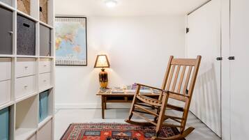 A room with a wooden rocking chair, a globe map on the wall, and a bookshelf with storage bins.