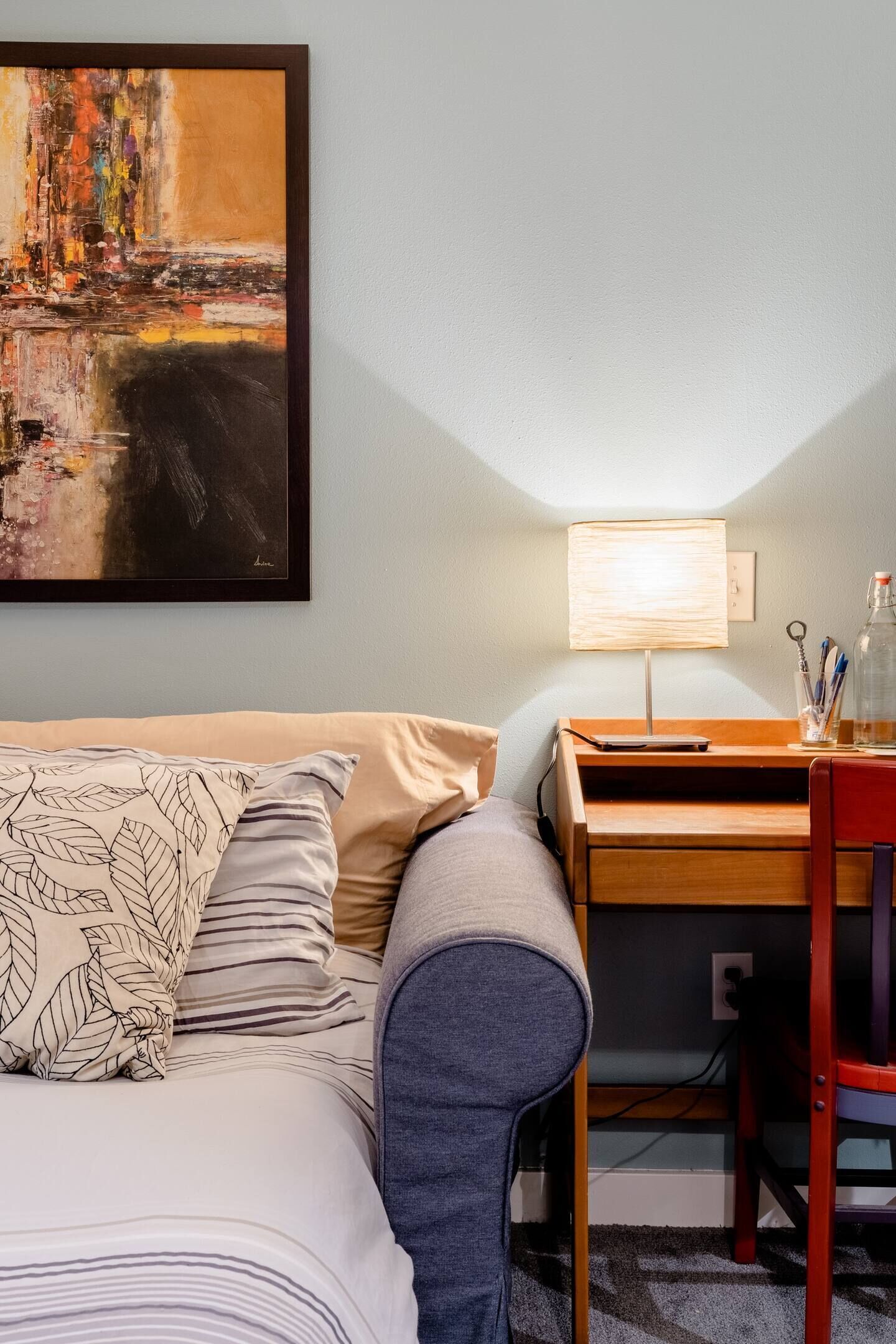 A neatly arranged hotel room with a bed, a desk, and a lamp.