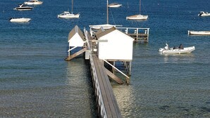 Un moll amb barques amarrades, un edifici blanc i aigua cristal·lina.