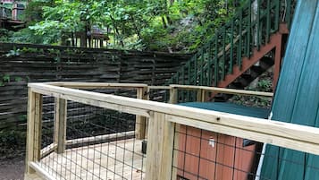 A wooden deck with a metal fence, surrounded by a wooden fence and greenery.