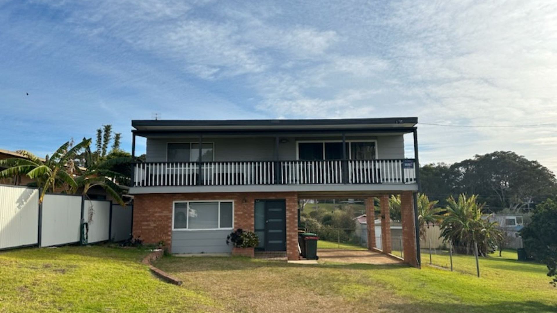 A two-story house with a balcony, a front door, and a small front yard.