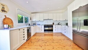 A modern kitchen with white cabinetry, a stainless steel refrigerator, and a wooden floor. - Poppy Cottage – delightful and pet-friendly cottage (Exeter)