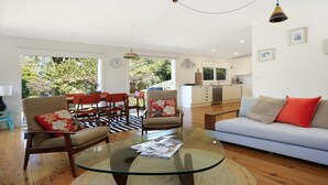 A spacious living room with a glass coffee table, a sofa, and a dining area with chairs. - Poppy Cottage – delightful and pet-friendly cottage (Exeter)