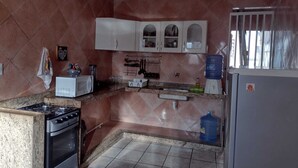 A kitchen with a stove, microwave, cabinets, and a water dispenser. - 1st floor house in Olinda, whitewashed house, 100 meters from the beach. (Casa Caiada)