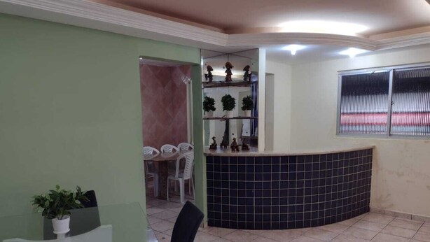A reception area with a tiled floor, a glass table, and chairs. There is a counter with a tiled backsplash and decorative items. A window with blinds is visible in the background. - 1st floor house in Olinda, whitewashed house, 100 meters from the beach. (Casa Caiada)