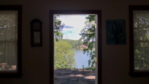 Une porte qui donne sur un paysage avec un lac, des arbres et un ciel dégagé.