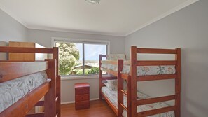 A dormitory room with bunk beds, a small wooden dresser, and a window with a view of trees. - 158 Wallaga Lake Road (WALLAGA LAKE)