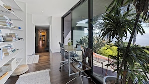 A modern interior with a glass door leading to a balcony, a wooden floor, and a bookshelf. - Award-winning ocean view luxury master suite. Perfect romantic retreat (Tiburon)