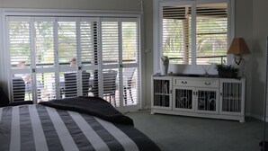 A bedroom with a bed, a nightstand, a lamp, and a window with blinds.