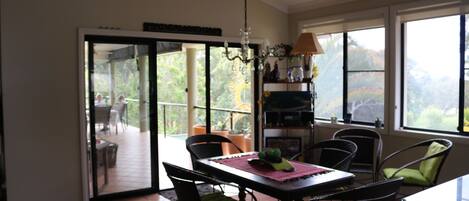 A dining area with a table, chairs, and a view of the outdoors through a glass door.