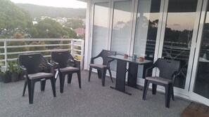A balcony with four chairs and a table, potted plants, and a view of a residential area. - C'EST LA VIE: Panoramic views. Bed & Breakfast (Mira Mar)