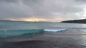 A beach with waves, a distant ship, and a cloudy sky. - C'EST LA VIE: Panoramic views. Bed & Breakfast (Mira Mar)