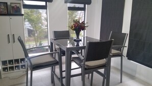 A dining area with a glass table, four chairs, a vase with flowers, and a view of the outdoors through large windows. - C'EST LA VIE: Panoramic views. Bed & Breakfast (Mira Mar)