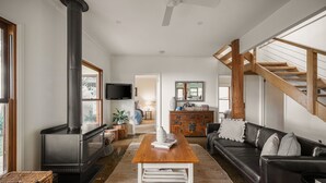Ein Wohnzimmer mit Kamin, Fernseher, Couch, Holz-Couchtisch und einer Treppe.