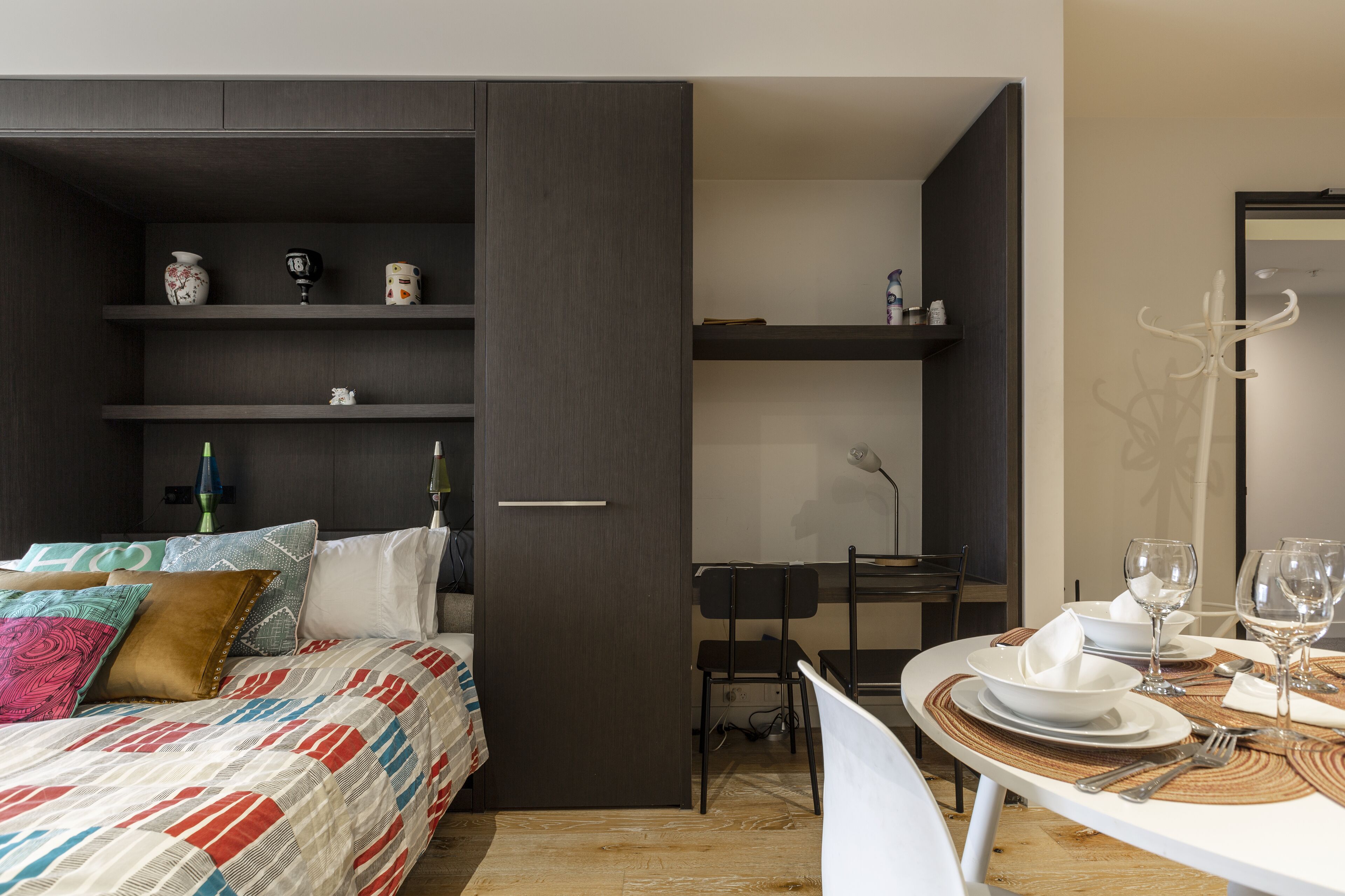 A compact bedroom with a bed, a desk, and a dining area.