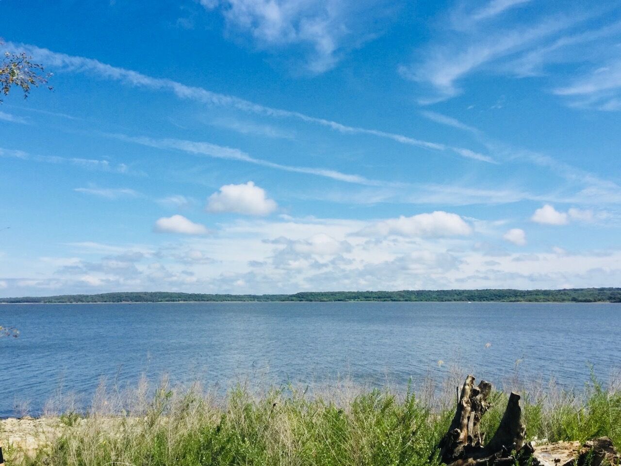 A calm lake with a clear sky and distant land.