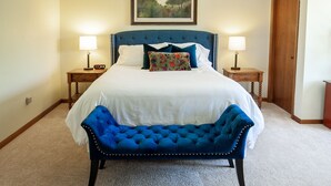 A neatly made bed with a tufted headboard, two bedside tables with lamps, and a bench in front of the bed. - Rock Creek Loft Guest House neighboring Lake Perry  (Ozawkie)