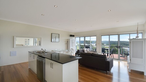 A modern kitchen with a central island, a dining area with a sofa, and a balcony with a view of the landscape. - Seascape  1 - Water views (BERMAGUI)