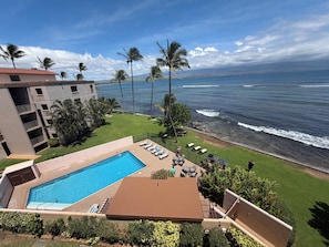 A hotel with a swimming pool, lounge chairs, and a view of the ocean.