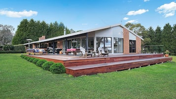 Una casa moderna con terraza, mobiliario exterior y zona de barbacoa.