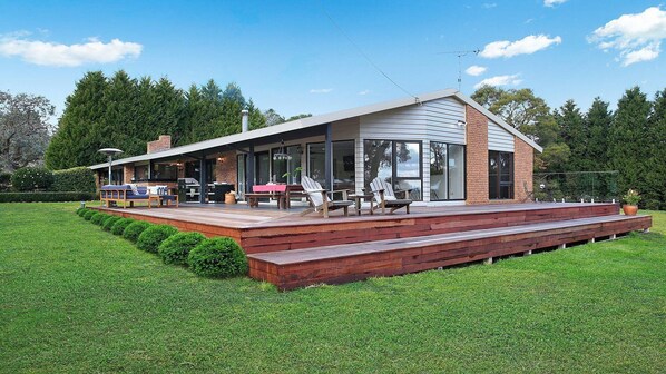 Ein modernes Haus mit Terrasse, Sitzgelegenheiten im Freien und einer Grillanlage.