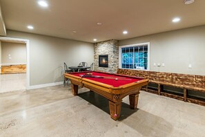 A pool table in a room with a stone wall and a window. - 7 bedroom Secluded Luxury Home.. (South Lake Tahoe)