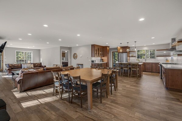 A spacious living area with a wooden dining table and chairs, a leather sofa, and a kitchen with wooden cabinets and a stainless steel refrigerator. - 7 bedroom Secluded Luxury Home.. (South Lake Tahoe)
