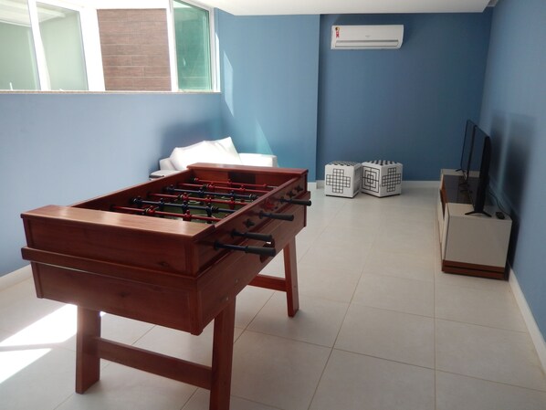 A room with a foosball table, a TV, and two dice cubes.