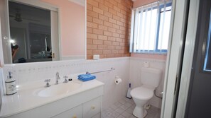 Bathroom features a sink, mirror, and toilet, with a towel and toilet paper roll.