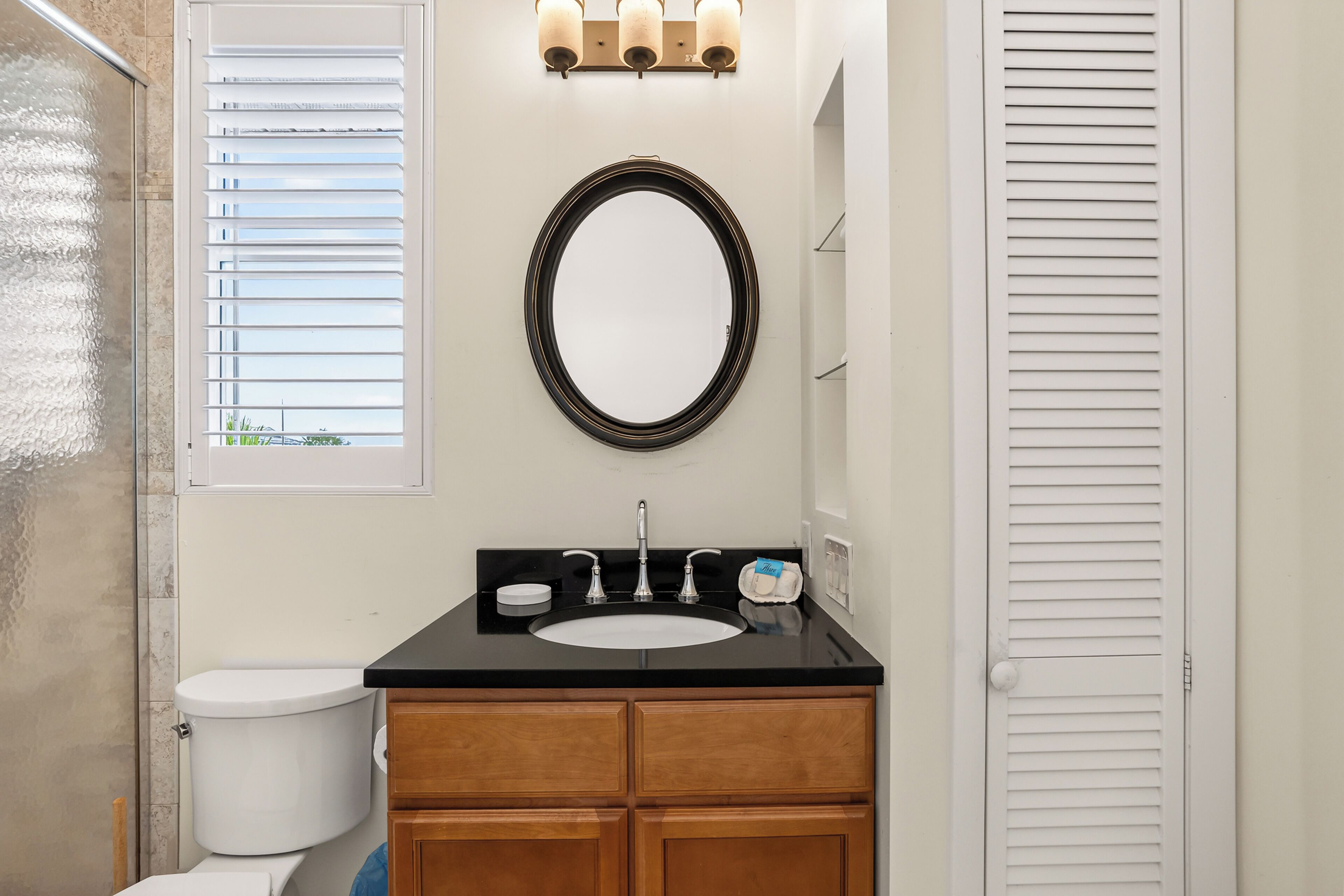 A bathroom with a toilet, sink, vanity, and a mirror.