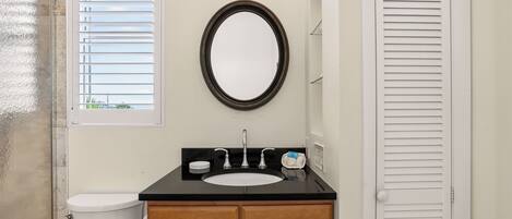 A bathroom with a toilet, sink, vanity, and a mirror.