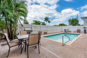 A backyard with a swimming pool, patio furniture, and a grill.