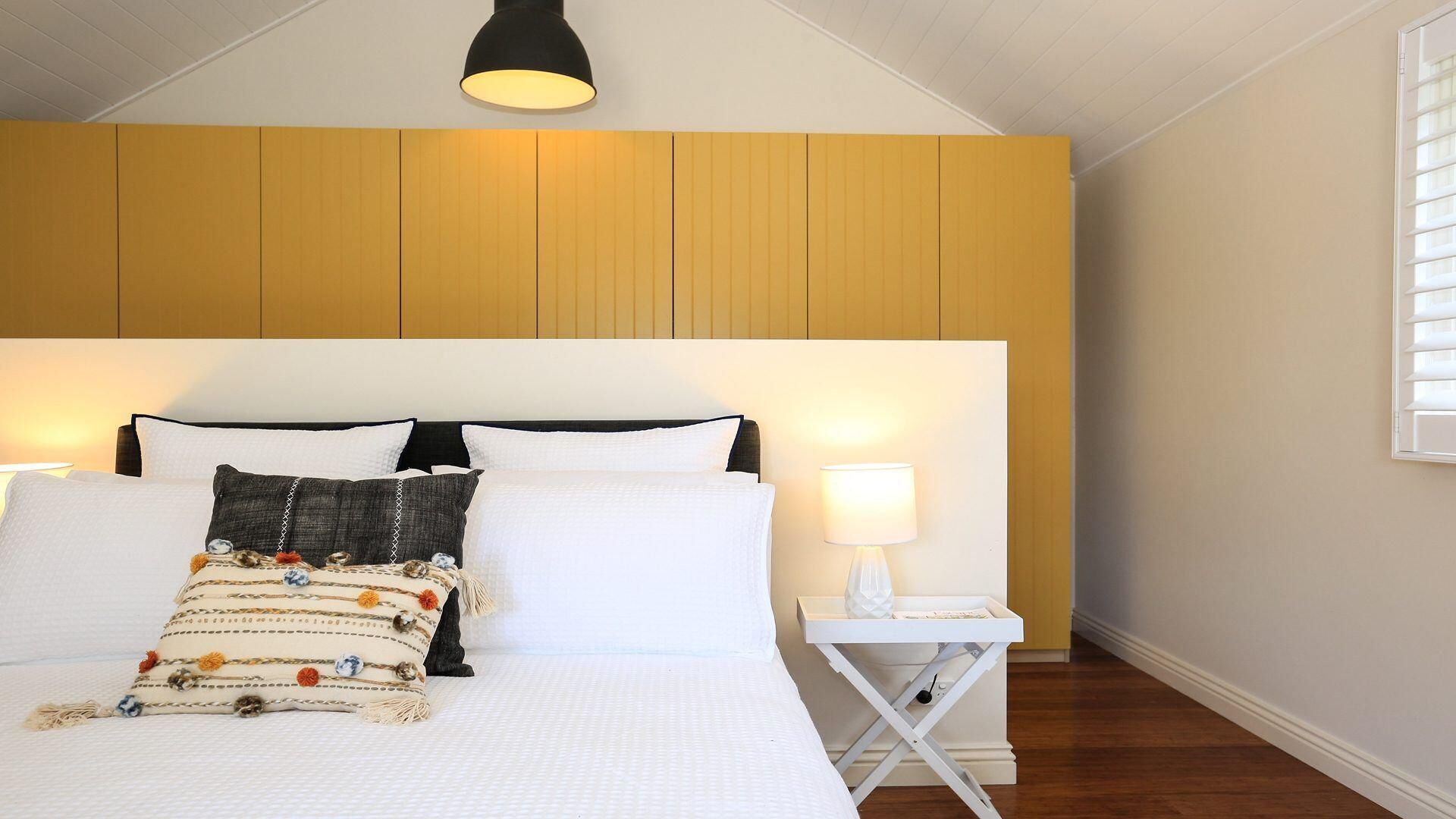 Une chambre à coucher avec un grand lit, une table de chevet avec une lampe et une fenêtre avec des stores.