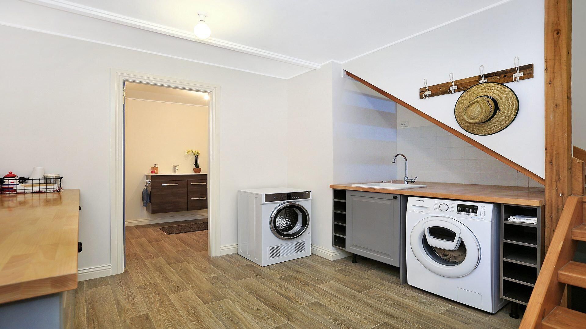 A compact kitchen with a washing machine, a small sink, and a wooden countertop.