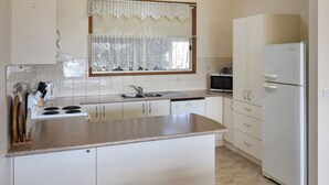 Une cuisine de taille réduite équipée d’une cuisinière, d’un évier, d’un four à micro-ondes et d’un réfrigérateur.